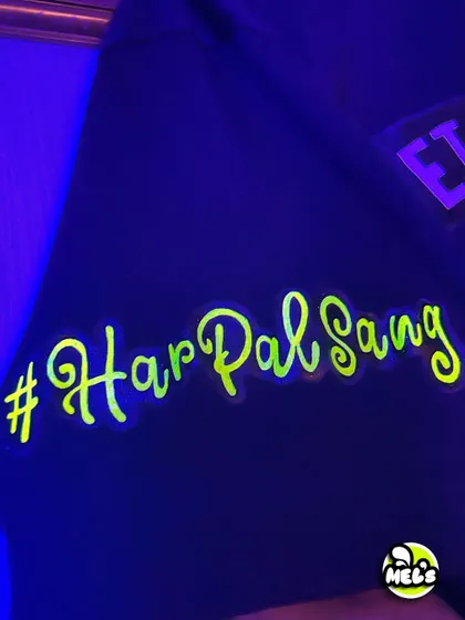The custom sleeve detail on the bachelor party T-shirt, featuring the wedding hashtag "#HarPalSang" in glowing neon script.