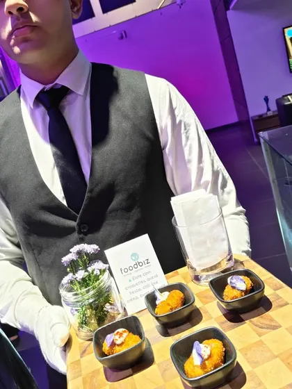 Our professionally attired server presents a tray of carefully crafted appetizers during a tequila soirée for Mercedes-Benz. The presentation on a wooden board with floral accents highlights our attention to detail.