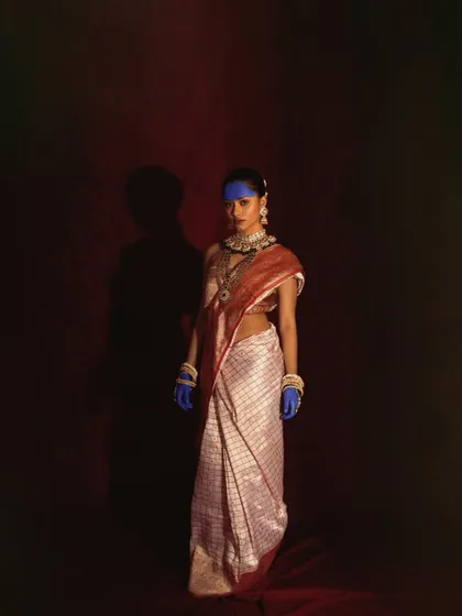 A full-length conceptual portrait playing with shadow and light. The dramatic use of negative space emphasizes the model's striking presence.