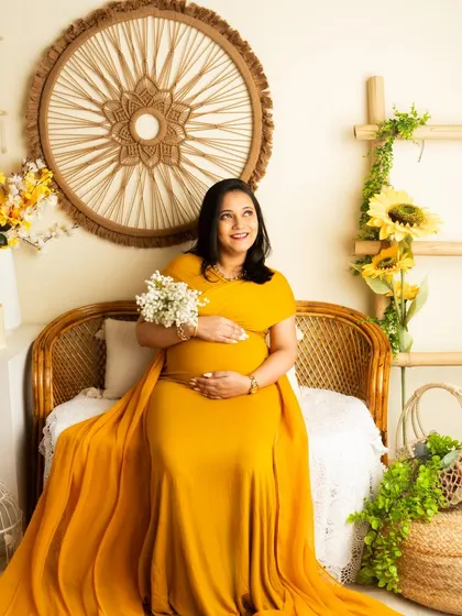 A cheerful portrait in a mustard yellow gown. The studio's boho setup is decorated with sunflowers to match the bright, happy color scheme.