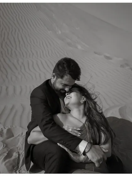 An intimate black and white portrait of a couple in the Dubai desert. The close framing and their joyful expressions create a powerful sense of connection and happiness.