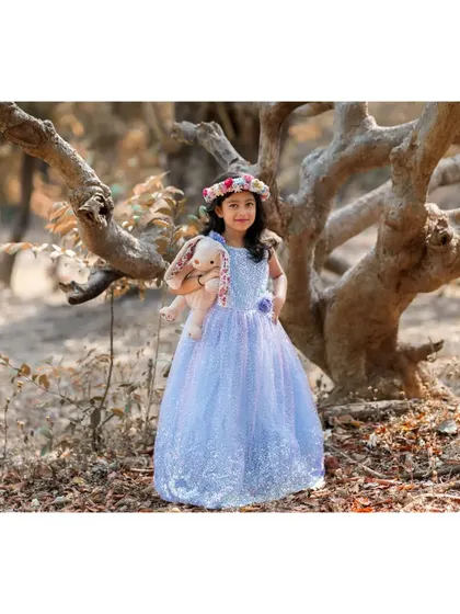 A full-length portrait of Brishka in her sparkling blue gown, standing in a forest setting. This wide shot captures the enchanting, fairytale quality of her seventh birthday photoshoot.