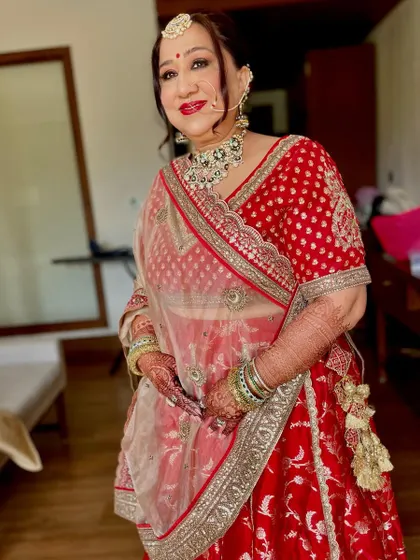 A classic and bold bridal look for this beautiful client. The bright red lip, defined eyes with a traditional nath, and an elegant updo create a stunning and timeless wedding day style.