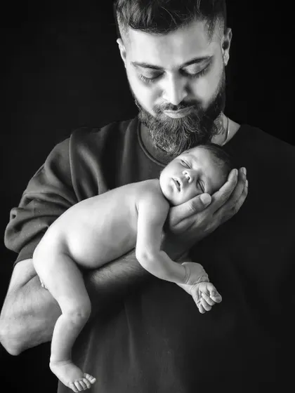 A father's gentle hold. This black and white portrait emphasizes the strength and tenderness in the way a dad holds his newborn child.