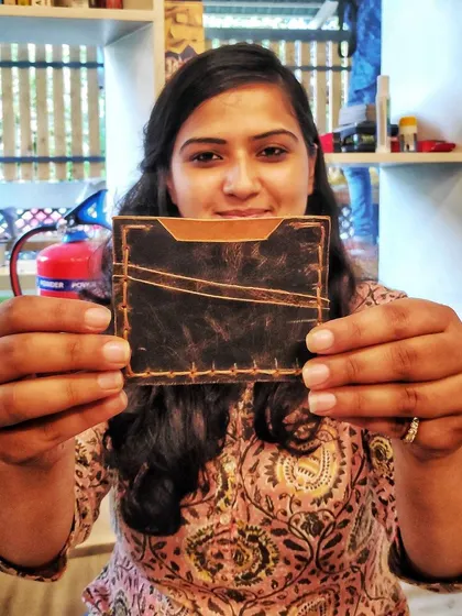 A duplicate of a participant proudly displaying her finished leather wallet. The satisfaction of creating something from scratch is a key part of the Kānike experience.