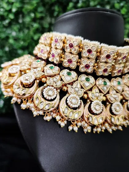A close-up of a multi-layered kundan choker for rent. This piece features floral motifs with red and green stones, perfect for a traditional bride.