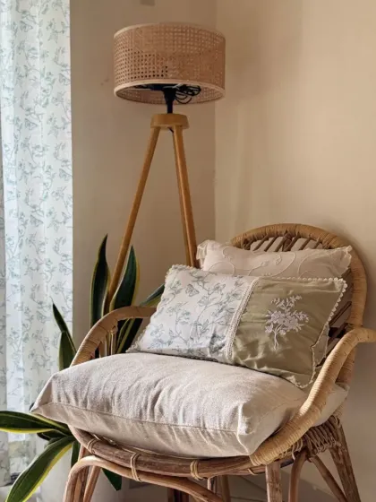 A still shot of the peaceful corner, highlighting the textures of the wicker chair and the soft cotton of our custom cushion covers. The combination of different prints in a similar color palette creates a harmonious look.