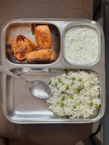 A simple, high-protein meal of pea rice with pan-fried salmon and a side of raita.