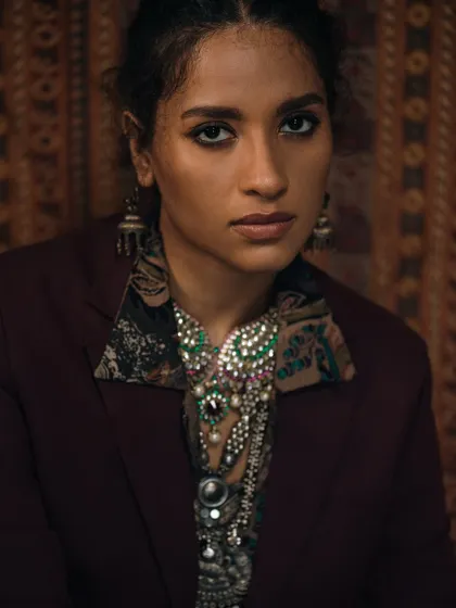 This direct-to-camera shot showcases how statement jewellery can frame the face. The rich, warm tones complement the traditional design of the pieces.