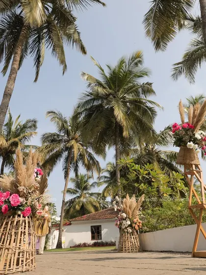 We created a "nature's aisle" for this tropical-themed event, lining the pathway with large rustic baskets filled with pampas grass and pink roses. This design beautifully blends with the outdoor venue and its towering palm trees.