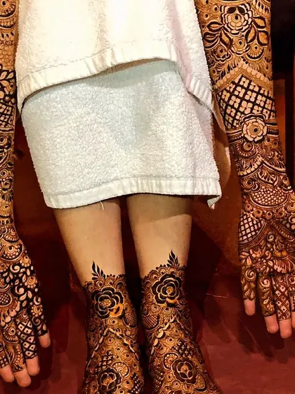 This is our complete bridal mehendi service, with rich, dark henna stain covering hands to elbows and feet. The cohesive design features beautiful rose motifs and demonstrates the full, stunning effect for your big day.