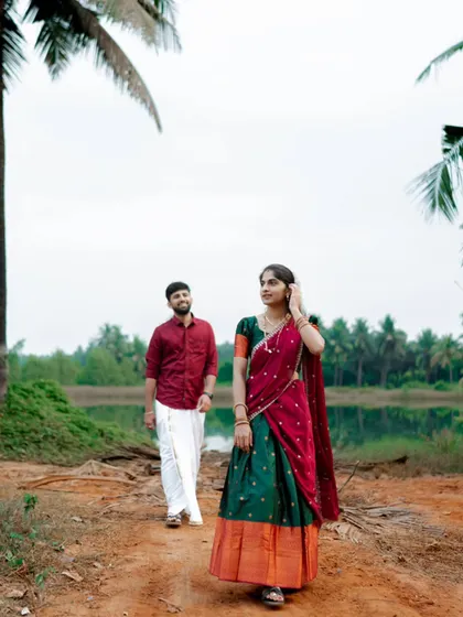 A candid moment as the couple walks along a rustic path in a village near Mangalore. The groom follows his bride, capturing a natural, unposed scene.