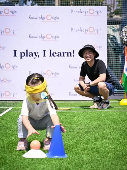 A child works on a blindfolded sensory game, guided by her father.