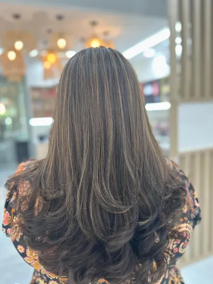 A perfect example of our sun-kissed highlights. We added fine, natural-looking streaks to create depth and texture, finished with a layered cut and soft curls. This is a popular choice for clients who want to brighten their look without a drastic change.