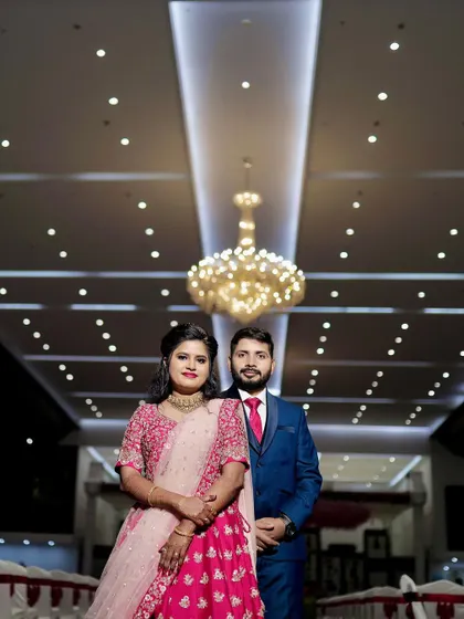 A beautiful portrait of the couple at their wedding reception. The grand chandelier and the elegant hall decor create a sophisticated and celebratory atmosphere.