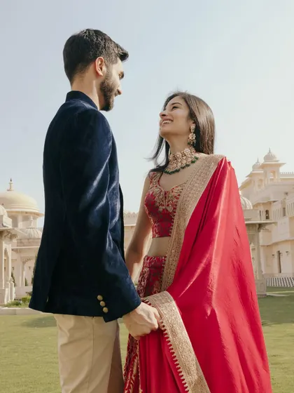 A low-angle shot of Nikita and Rishabh looking at each other, with the majestic Udaivilas palace behind them. This perspective adds a sense of grandeur.
