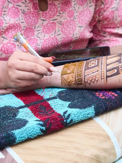 I make sure to document the process and artistry of the mehendi. This close-up shows the incredible skill of the artist as they create a detailed design.