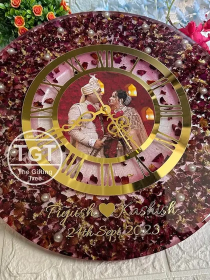 The large size of this clock allows for a dense arrangement of flower petals, creating a rich, textured background. The couple's names and wedding date are added at the bottom.