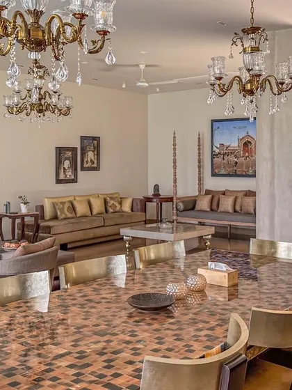 This image captures the vibrant and eclectic nature of the living and dining space. The mix of traditional Indian art, modern furniture, and classic lighting fixtures creates a unique and personalized home.