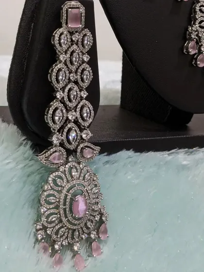A detailed view of the long, statement earrings from the pastel pink AD set.