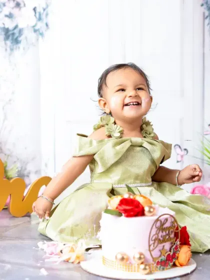 A moment of pure delight during a first birthday cake smash. This little girl's joyful expression is what makes these sessions so special and fun.