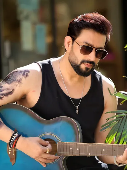 Actor Aadesh Chaudhary in a rugged, casual look. This outdoor shot with a guitar shows a different, more relaxed character type, adding another layer to his portfolio.