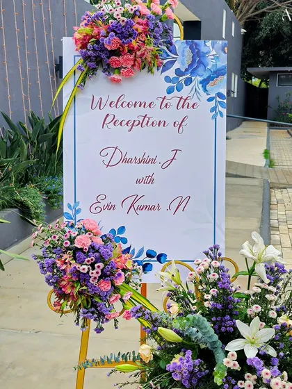 A beautiful and personalized welcome sign for a reception. The sign is adorned with lush bouquets of colorful flowers, offering a warm and personal greeting to guests.