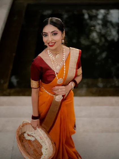 An elegant portrait featuring a classic orange and maroon saree. I used soft lighting to highlight the traditional jewelry and the model's graceful expression, with a basket of flowers adding a touch of softness.