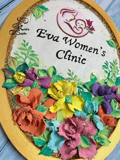 A custom oval nameboard created for "Eva Women's Clinic," featuring the clinic's logo and a beautiful arrangement of colorful flowers. A thoughtful and professional gift.