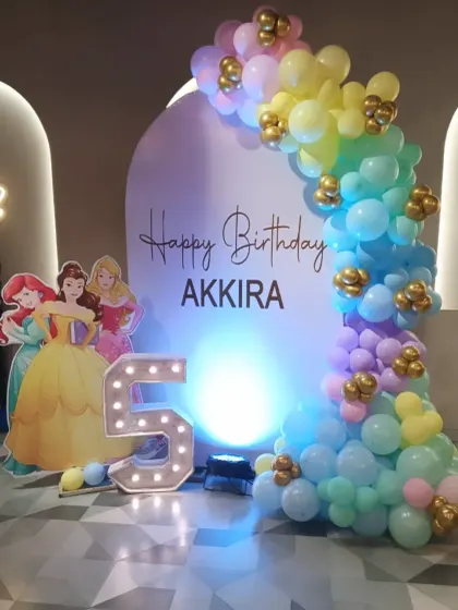A Disney Princess theme for Akkira's 5th birthday. The setup includes a princess cutout, a marquee number '5', and a beautiful pastel rainbow balloon arch.