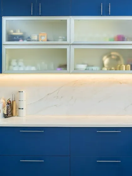 A detailed shot of the blue kitchen, highlighting the clean lines of the handleless cabinets, the under-cabinet lighting, and the frosted glass uppers that add a touch of modern elegance.