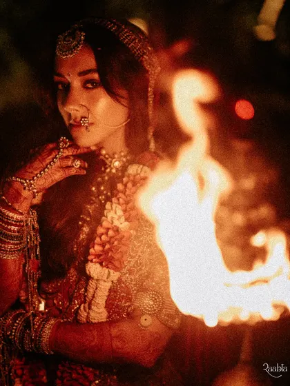 The bride, Tvisha, holding a torch, her face illuminated by the flame. This is a powerful and unconventional bridal portrait that is both fierce and beautiful.