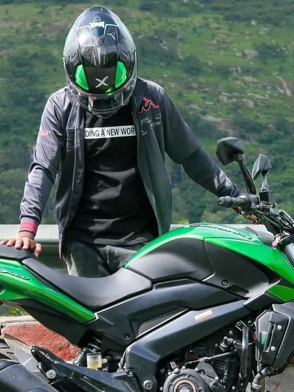 A rider in full gear, standing proudly with his Dominar 400 at Nandi Hills.