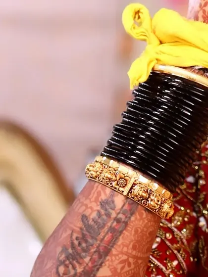 A close-up of the bride's hands, showing her intricate mehndi design and traditional black bangles, which are an important part of the bridal attire.