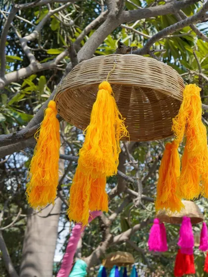 Another look at the hanging baskets, this time with bright yellow tassels that tie into the Haldi theme. They look beautiful hanging from trees and add movement to the decor.
