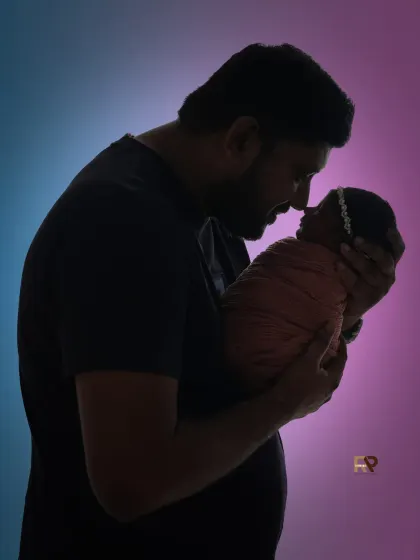 A touching silhouette of a father holding his newborn baby close, showcasing the powerful bond between parent and child. This artistic shot uses dramatic lighting to create a timeless and emotional family portrait.