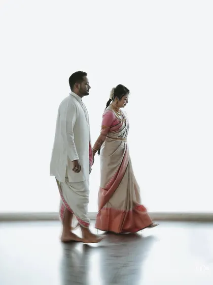 A beautiful, minimalist portrait of the couple walking hand-in-hand against a clean white background.
