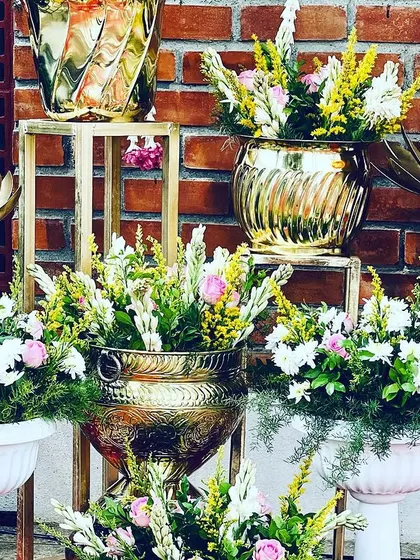 A close-up of the decorative elements used for the Seemantham, including brass pots filled with flowers and lotus-shaped lamps.