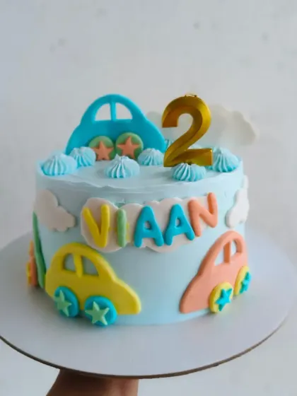 A colorful cars themed cake for a 2nd birthday, with cute, cartoonish fondant cars and clouds.