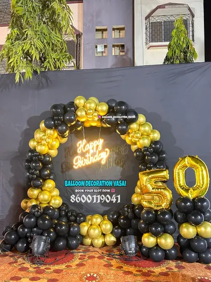 A 50th birthday outdoor celebration with a black and gold theme. The balloon ring and foil numbers create a perfect photo spot.