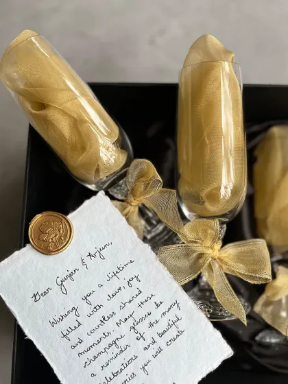 Even simple gifts can be elevated with thoughtful wrapping. Here, we've wrapped champagne glasses and included a beautiful handwritten note on textured paper, sealed with our signature wax seal.