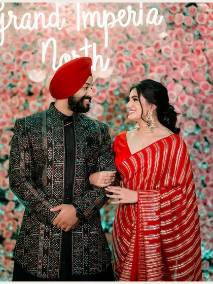 A joyful portrait of the couple against a wall of pink flowers. Their matching smiles and comfortable pose radiate happiness and the celebratory spirit of their engagement.