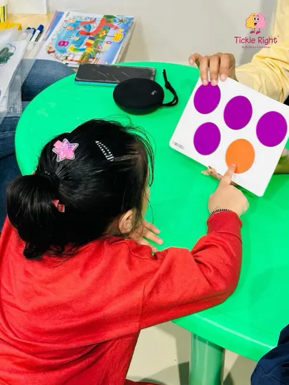 A young girl points to an image on a flashcard, her focus demonstrating how our visual learning tools capture a child's attention and aid in memory development.