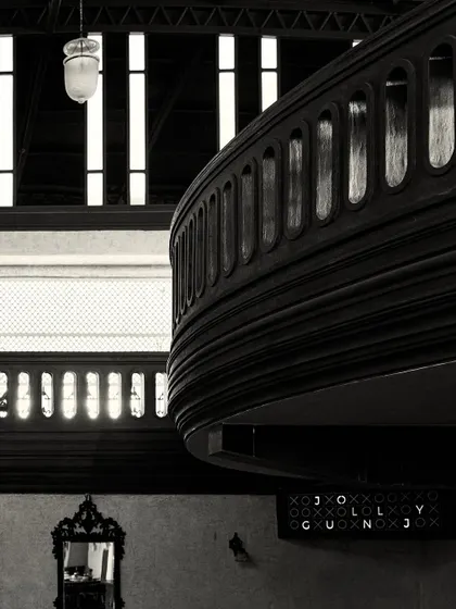A composition showing the layers of the space: the mezzanine balcony, a vintage mirror below, and the tall windows in the background.