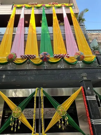 The facade of a modern house decorated with colorful drapes in yellow, pink, and green for a pre-wedding function.