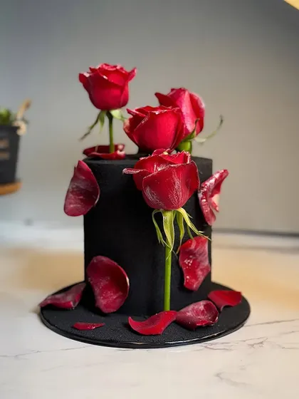 A beautiful and dramatic black cake with delicate red roses.