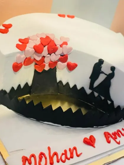 A heart-shaped anniversary cake with a silhouette of a dancing couple under a tree of hearts. This design tells a beautiful story.