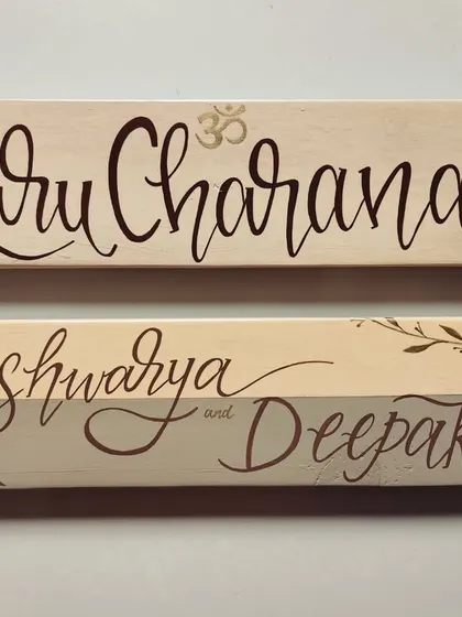 Simplicity and elegance in a set of two name plaques. Created with soft, minimal tones and delicate leafy details, these pieces for "Guru Charana" and "Aishwarya and Deepak" bring a sense of calm.