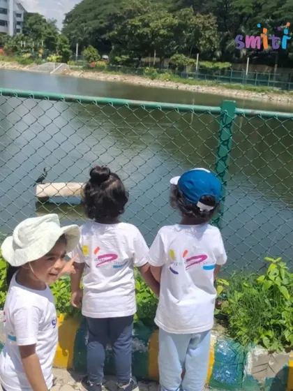 Three children look out over the water, observing the birds. These quiet moments of observation are powerful learning opportunities.