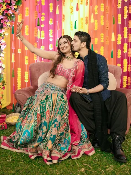 A fun selfie moment during the Sangeet, with the groom stealing a kiss. It's all about capturing your personalities.